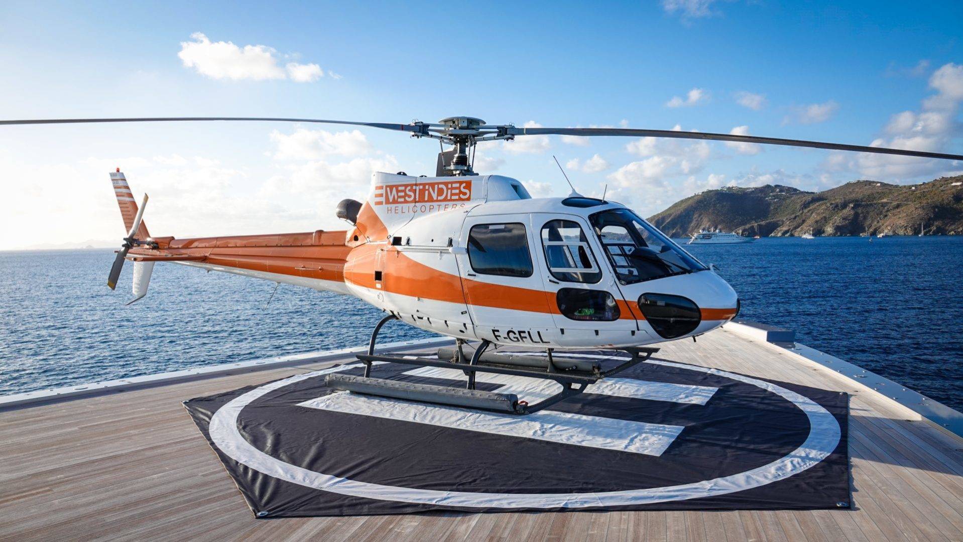 Orange-and-white West Indies Helicopters aircraft on a St. Barts helipad